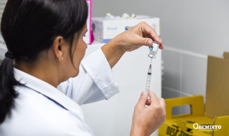 Profissional de saúde com vacina nas mãos