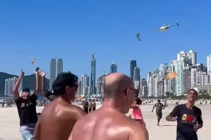Influenciadora chega de helicóptero e lança dinheiro em praia de Balneário Camboriú