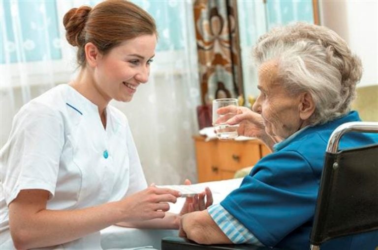 Female Nurse Giving Senior Woman Medical Pills