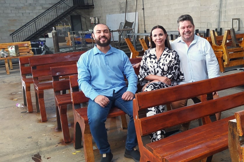 Empresários que produzem produtos com lixo e uma mulher. Todos sentados em um banco.