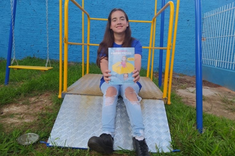 Adolescente surda de Umuarama segurando o livro que foi inspirado nela