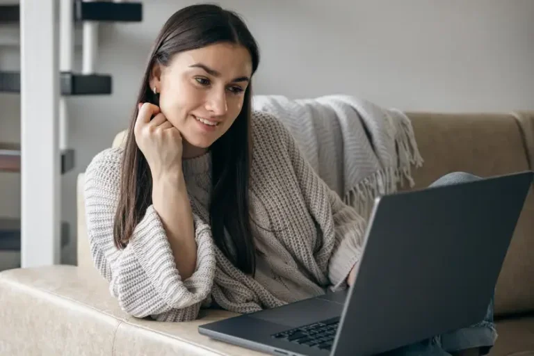 Mulher banca sentada olhando para um notebook. Foto ilustra a matéria sobre os concursos abertos no Paraná