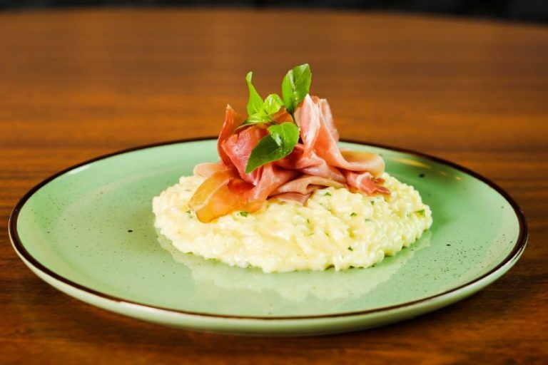 risoto com parma dentro de um prato verde em cima de uma mesa marrom