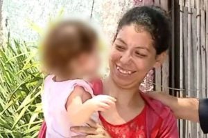 Na foto, a mãe de Eloah segurando a filha nos braços durante entrevista.