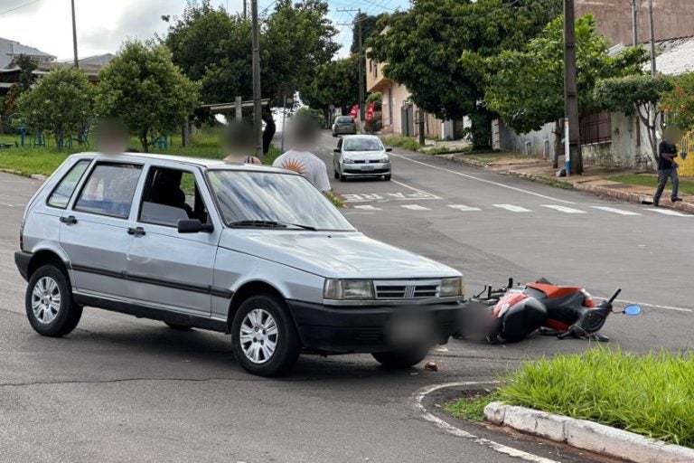 Condutora de Biz colide em automóvel e sofre ferimentos. Na foto, os ocupantes do carro envolvido na colisão, ao lado do veículo e da motoneta caída.