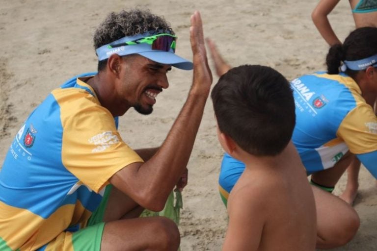 Acadêmicos de Umuarama participando do Verão Maior Paraná. Na foto, um dos voluntários fazendo um "high-five" com uma criança.