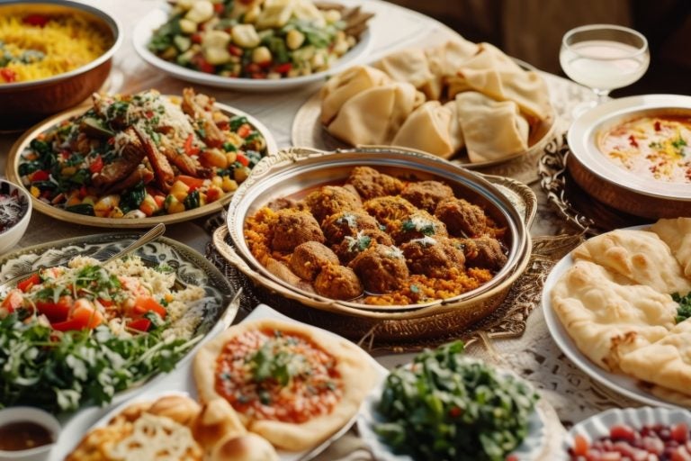 Imagem de uma mesa com vários pratos de comida árabe.