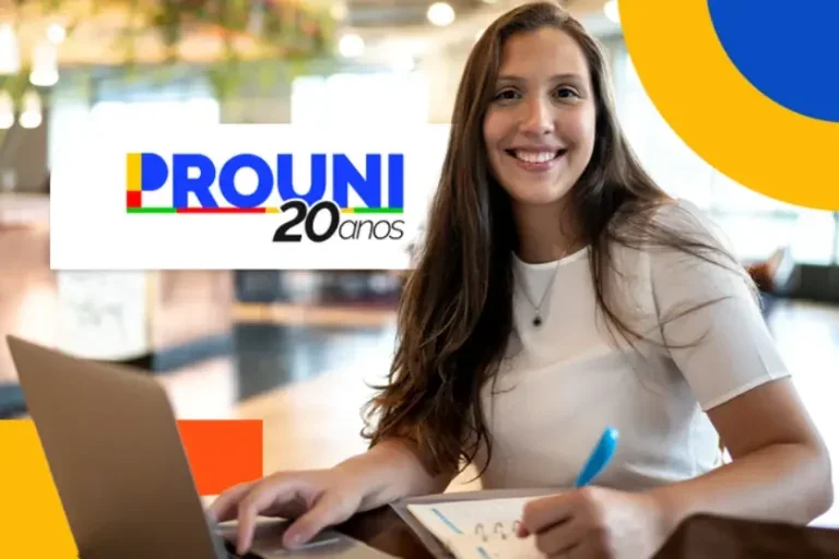 Jovem branca sorrindo olhando para a câmera sentada em uma cadeira usando um notebook e escrevendo com uma caneta azul em um caderno