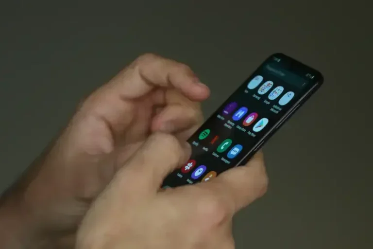 Mãos de uma pessoa manuseando um celular em ligações indesejadas.