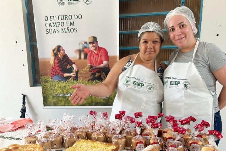 Duas mulheres aparecem agraçadas, mostrando itens que produziram nas oficinas