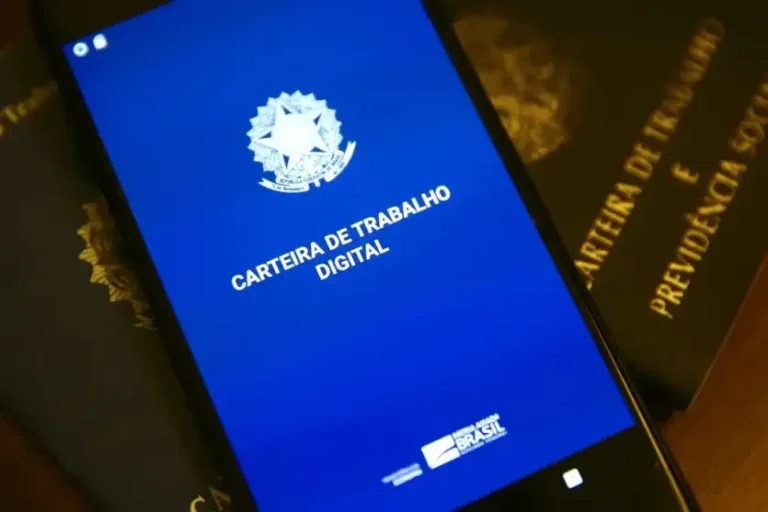 Foto de um celular mostrando a carteira digital de trabalho em cima de carteira de trabalho físicas. Foto para ilustrar a matéria de descontos do Inss atulizados.