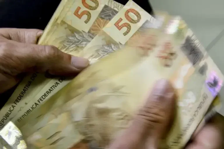 Mãos de um homem contando notas de cinquenta reais. Imagem para ilustrar matéria sobre novo salário mínimo