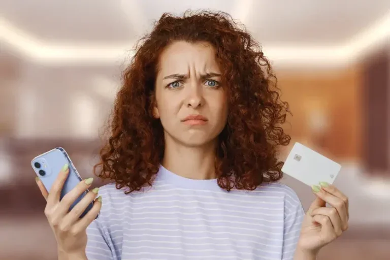Mulher branca confusa segurando um celular e um cartão. Foto para ilustrar matéria sobre 'Valor inbox': entenda como a prática nas redes sociais pode ser ilegal.