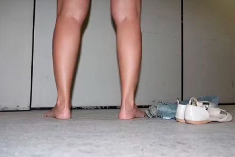 Revista íntima em presídios. Na foto, as pernas de uma pessoa descalça ao lado de um amontoado de roupas.