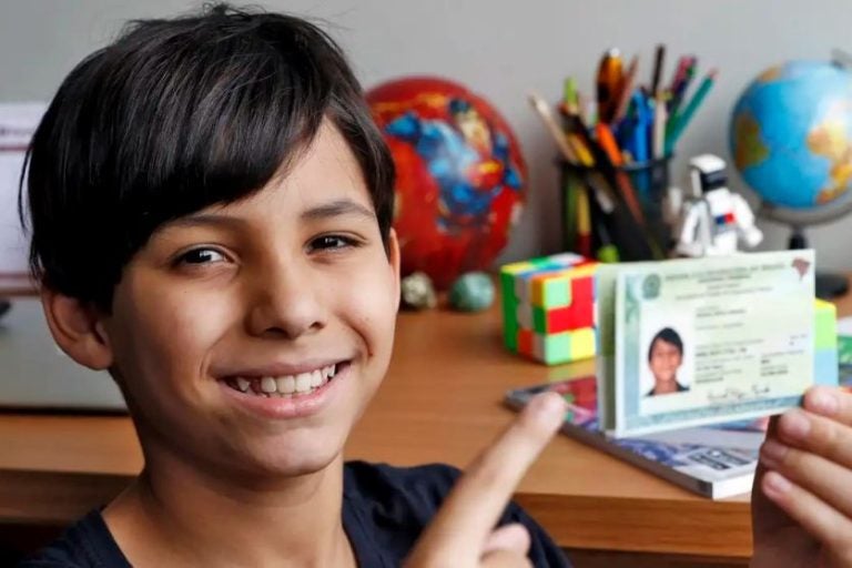 Carteira de Identidade Nacional. Na foto, um menino segurando o documento de identificação.