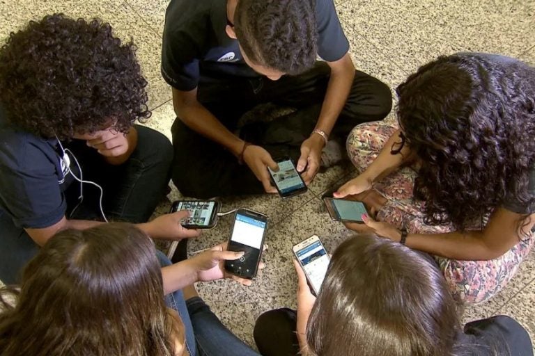 Decreto sobre proibição de celulares nas escolas é publicado. Na foto, crianças mexendo em smartphones.