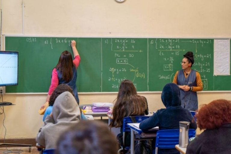 Olimpíada Brasileira de Matemática. Na foto, uma aluna escrevendo na lousa, ao lado de uma professora.