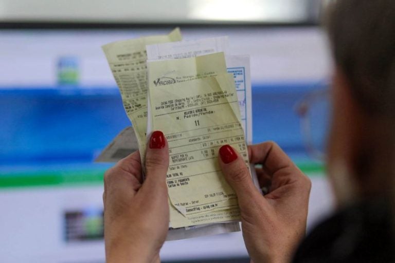 Nota Paraná devolve créditos aos consumidores. Na foto, uma consumidora olhando um bilhete.