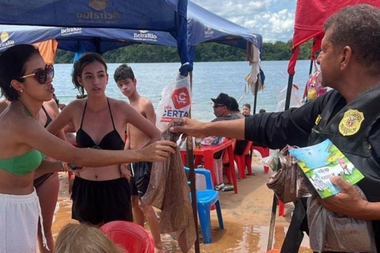 IAT nas prainhas do Noroeste do Noroeste. Na foto, um dos profissionais entregando um saco de lixo a uma banhista.