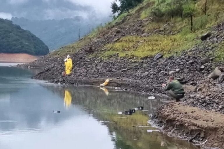 Caminhão cai em represa, espalha carga de tinta e deixa criança morta e pai desaparecido