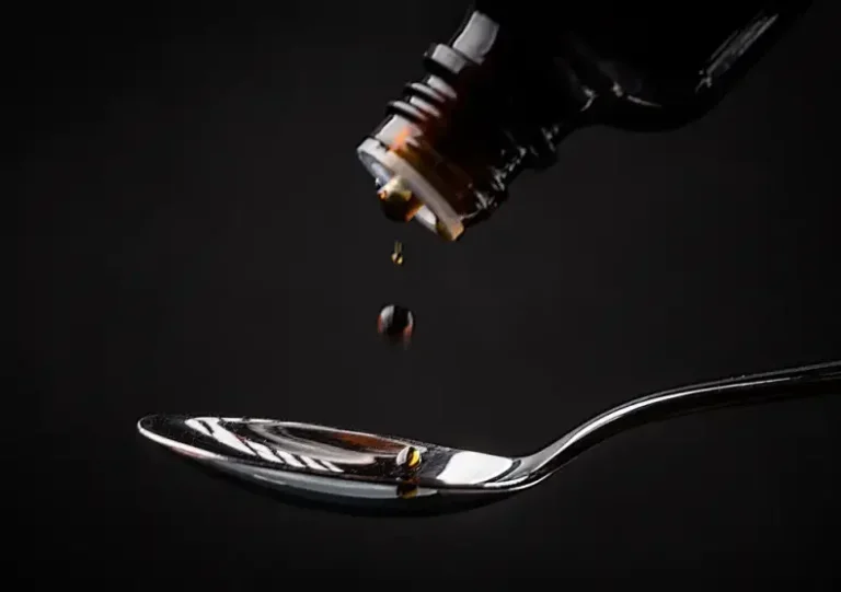 Na foto, um xarope sendo pingado em uma colher de metal para ilustrar o medicamento suspenso pela Anvisa.