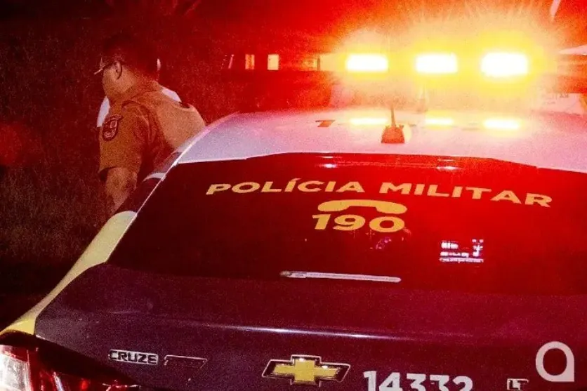 Foto de um policial militar ao lado de uma viatura para ilustrar a matéria do assalto em um comércio na Zona 1 de Umuarama.