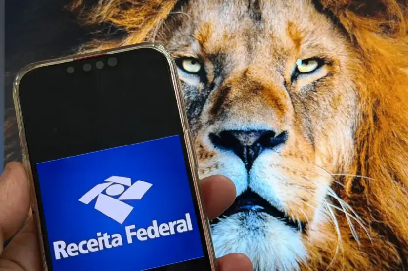 Celular com o brasão da Receita Federal com um leão ao fundo para ilustrar o pagamento do lote da malha fina do IR nesta quinta-feira.