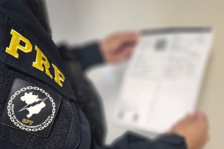 Na foto, um agente da PRF analisando um documento para ilustrar a situação em que o casal foi preso por apresentar documento falso em Guaíra.