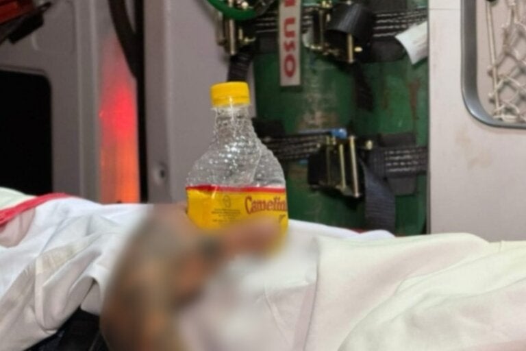 Na foto, a mão do homem agarrada à garrafa de bebida durante o atendimento médico.