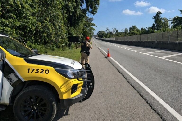 Policial rodoviário estadual ao lado de uma viatura enquanto fiscaliza a rodovia com radar móvel, para ilustrar a matéria sobre a Operação Dia do Trabalhador.