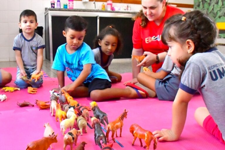 Crianças e uma professora interagindo durante uma atividade em CMEI de Umuarama.