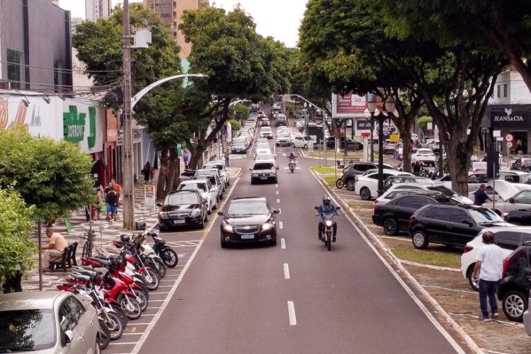 Foto das ruas do comércio de Umuarama em um dia movimentado, com pedestres, veículos e lojas.