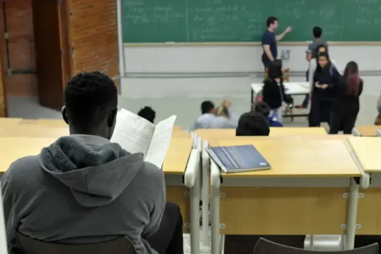 Foto de um aluno negro assistindo uma aula em uma universidade.