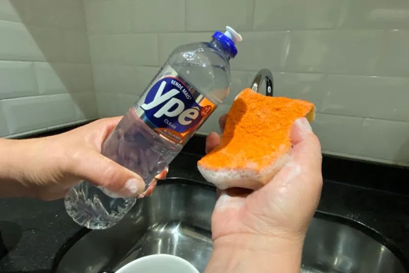 Pessoa usando detergente Ypê para lavar a louça.