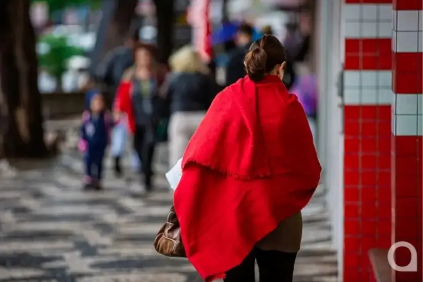 Foto de pedestre com roupas de frio em uma rua de Umuarama.