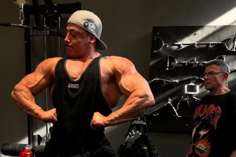 Fisiculturista Gabriel Ganley de camiseta regata e boné, exibindo braços musculosos.