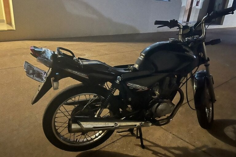 Foto da motocicleta apreendida pela PM após a fuga no Centro de Umuarama. É uma Titan de cor preta com a placa levantada.