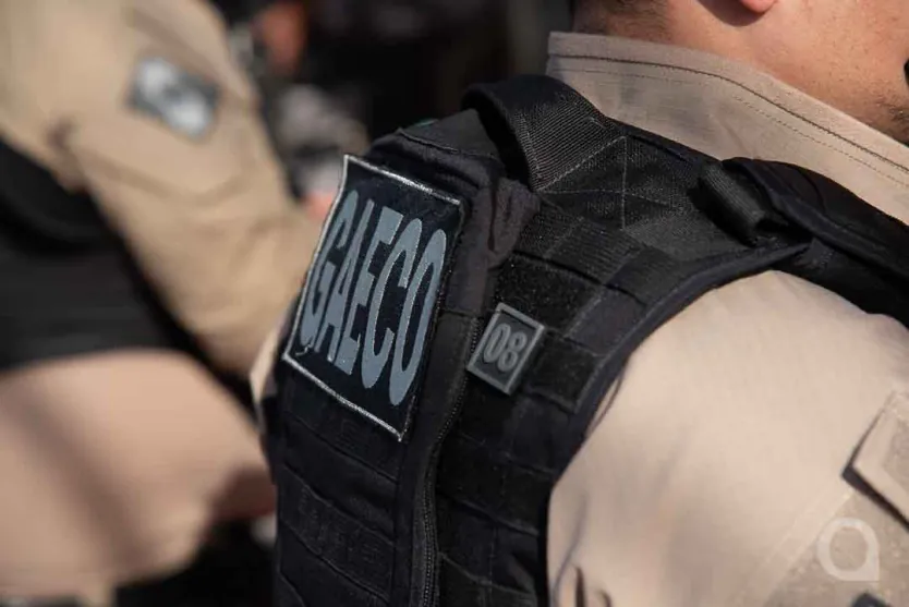 Foto de um policial com um colete do Gaeco.