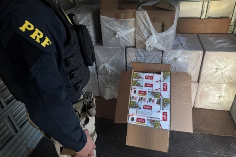 Cigarros contrabandeados apreendidos em Alto Paraíso. Na foto, um policial ao lado da carga.