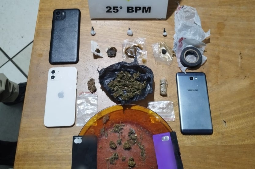Foto de uma mesa com porções de drogas, celulares e cartões de crédito.