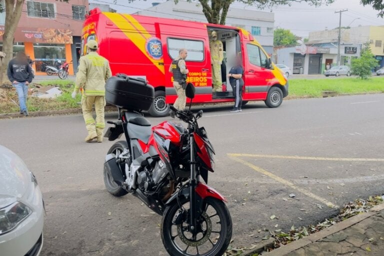 Foto da moto envolvida no acidente na avenida Brasil e, ao fundo, uma ambulância do Siate.