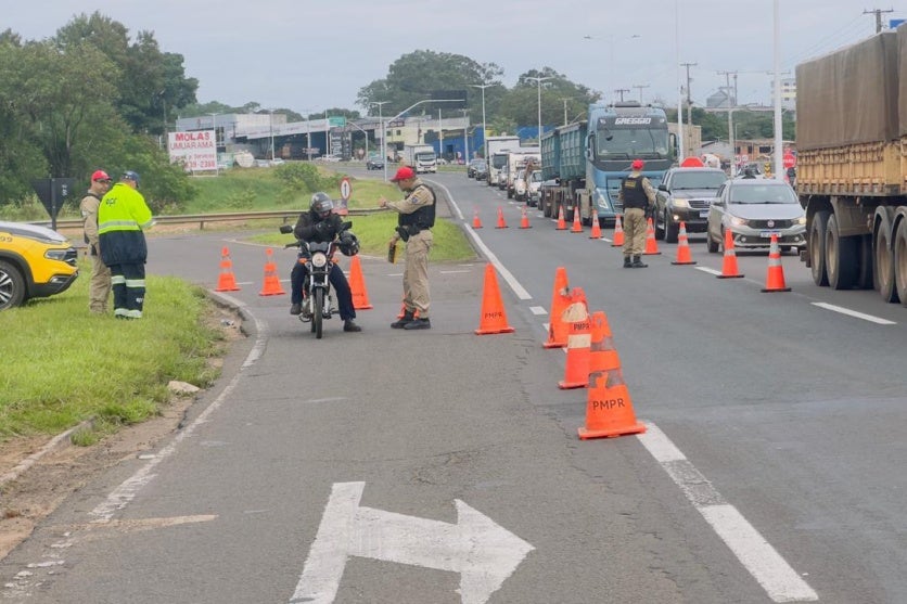 Foto de um motociclista sendo abordado durante uma ação de conscientização na PR-323, em Umuarama.