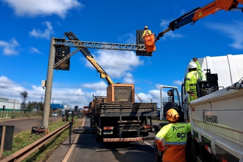 Equipes realizando a instalação de uma placa em rodovia.