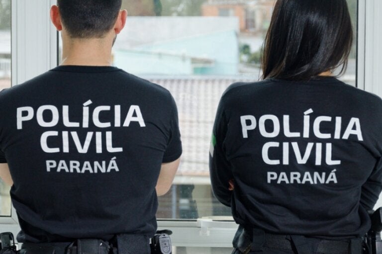 Dois policiais civis vistos de costas.
