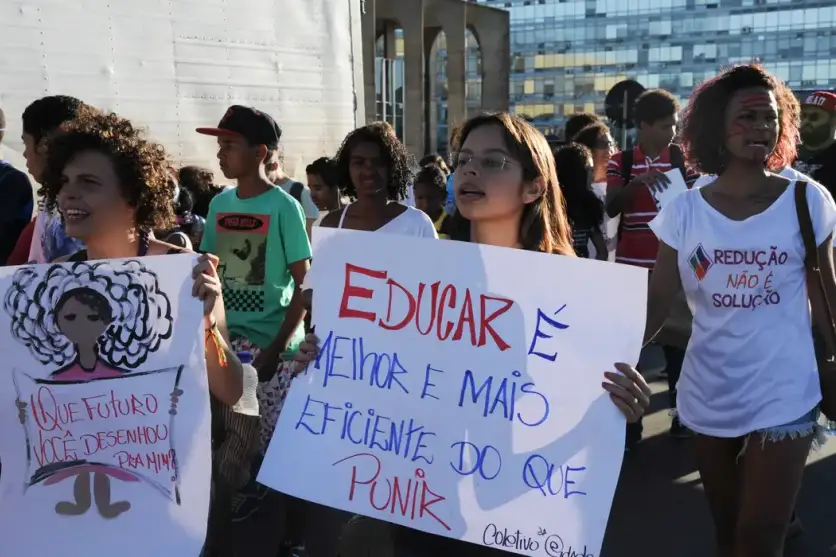 Pessoas com cartazes em protesto contra a redução da maioridade penal.