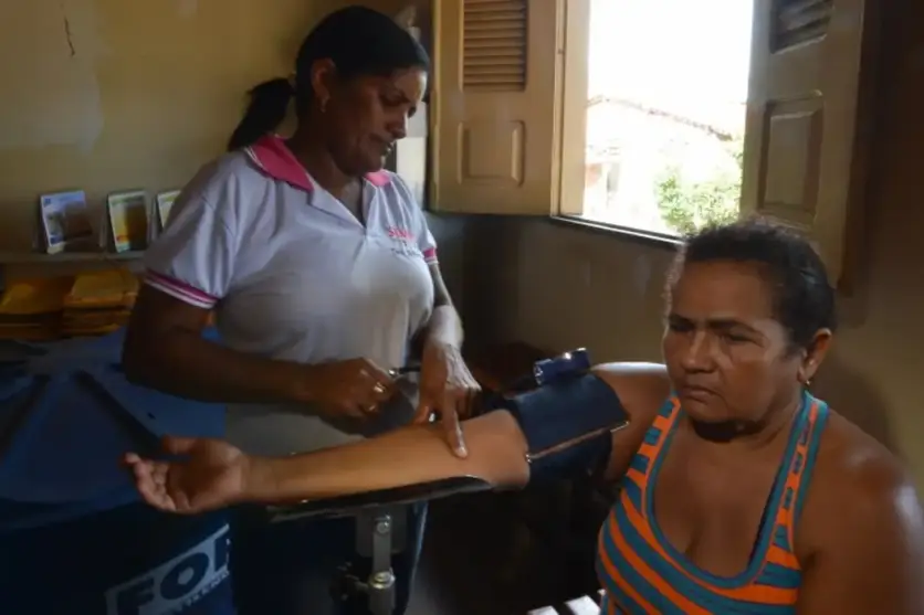 Agente de saúde aferindo pressão de uma paciente.