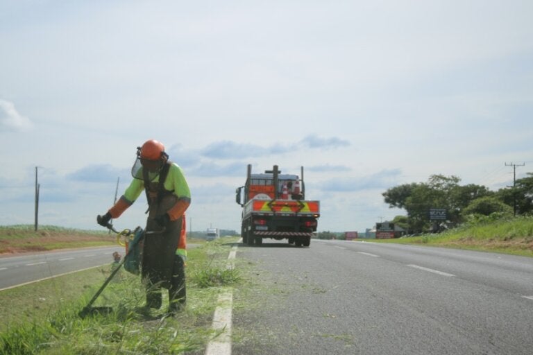 Trabalhador da EPR realizando roçada em grama dde canteiro central de rodovia.