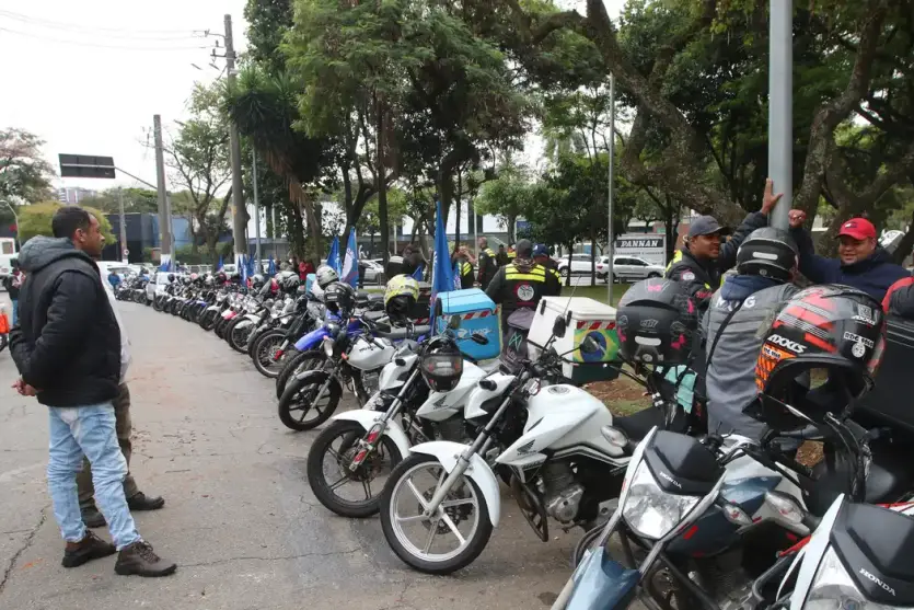 Motociclistas e seus veículos parados em um estacionamento.