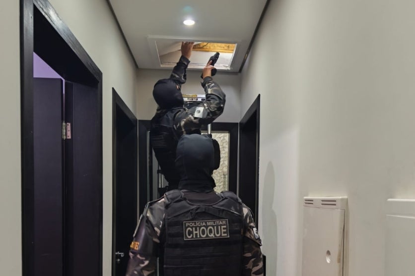 Equipes da choque conduzindo buscas a explosivos em uma residência.