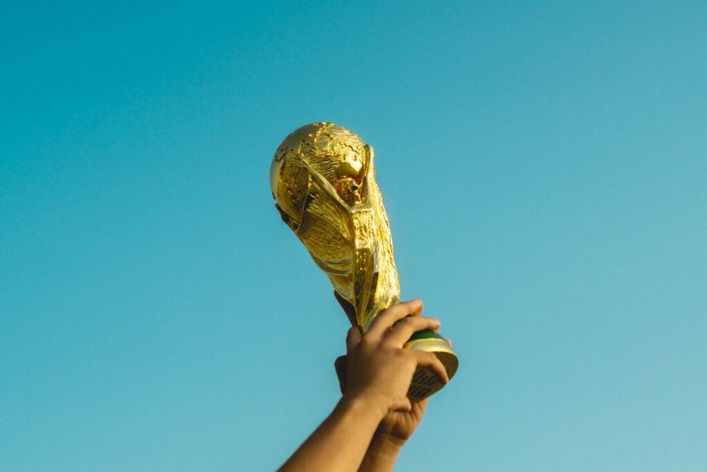 Jogador de futebol levanta o troféu da Copa do Mundo com as duas mãos